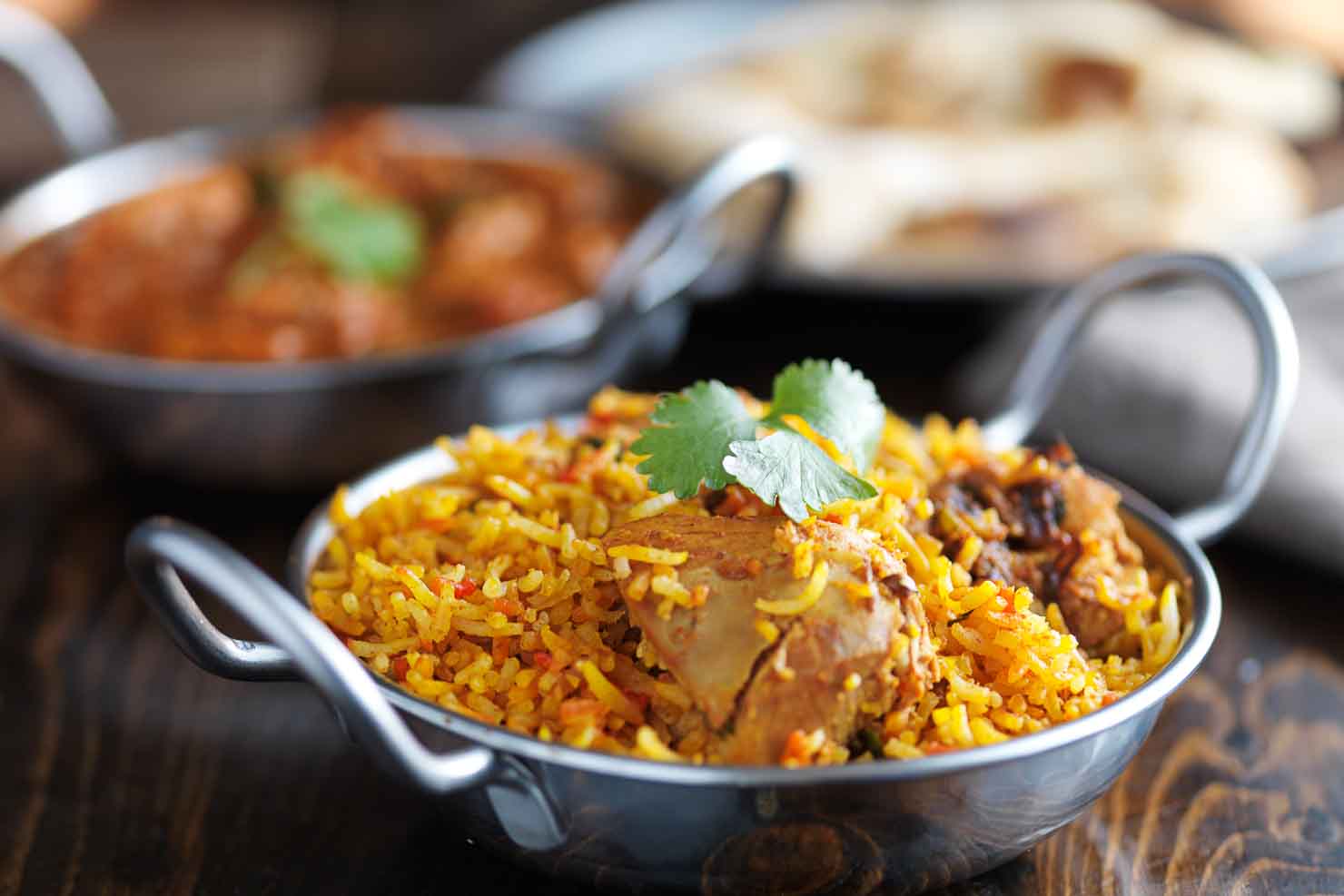 balti dish with indian chicken biryani and curry in the backgrou